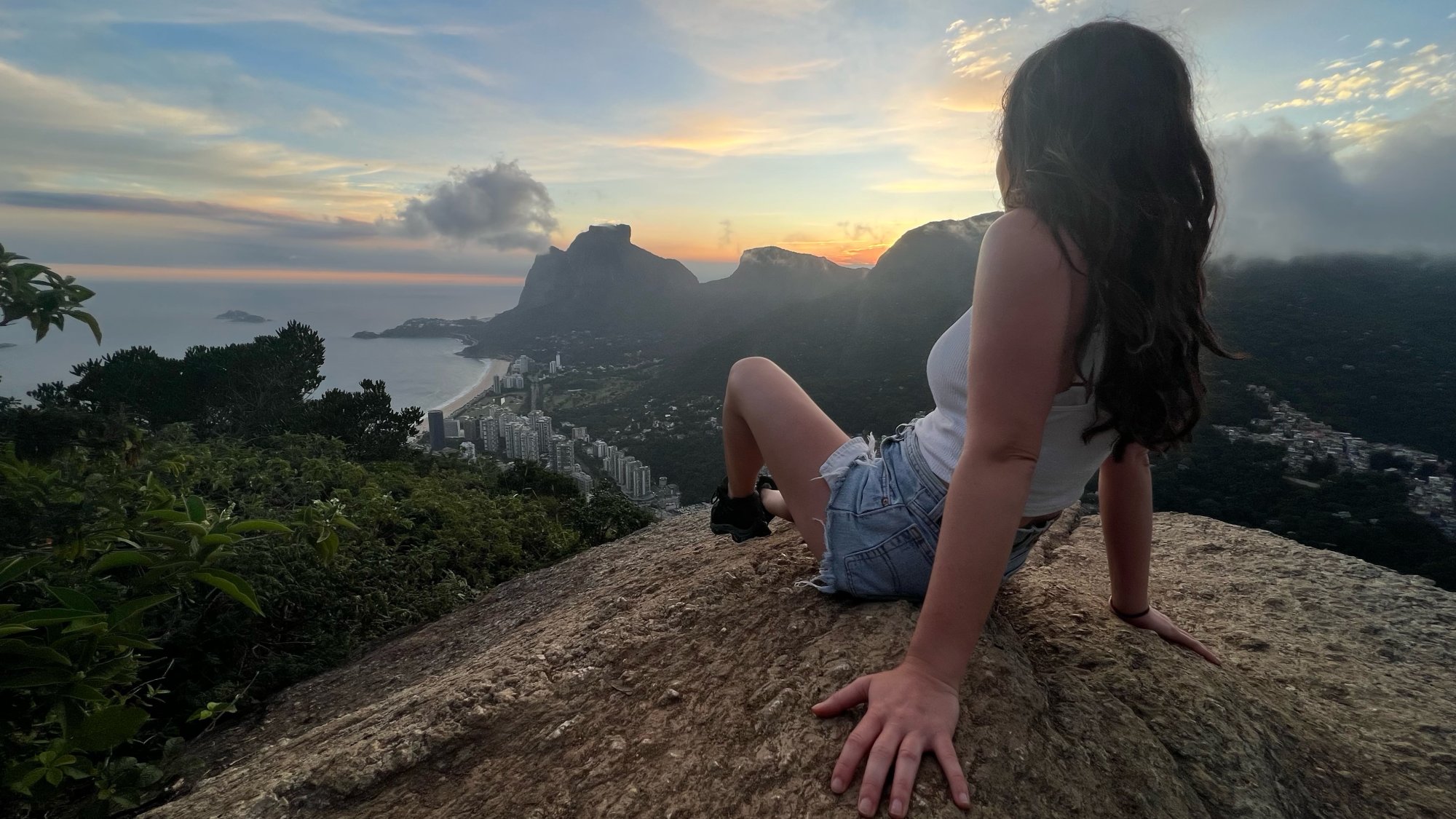 Lauren sitting on a rock looking across the mountains at sunset